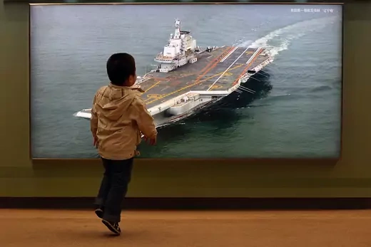 A Chinese boy passes a photo of China’s first aircraft carrier at an exhibition. 