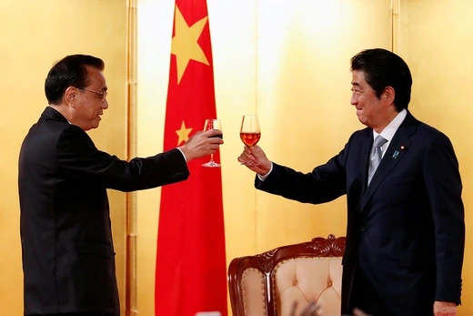 Chinese Premier Li Keqiang toasts with Japanese Prime Minister Abe Shinzo in front of Chinese flag.