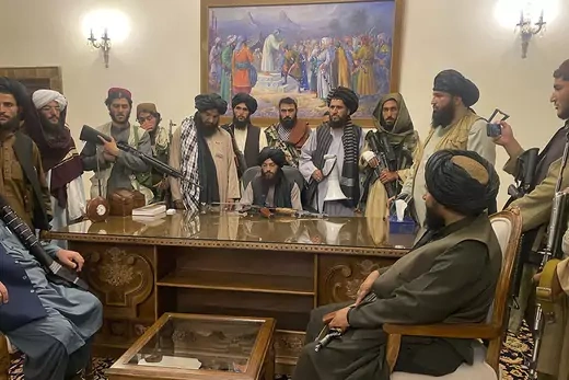 Taliban fighters stand behind a desk in the Afghan presidential palace.