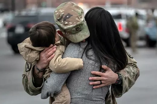 A U.S. service member hugs a woman and child after returning from Afghanistan.