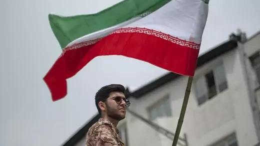 A member of Iran's Islamic Revolutionary Guards Corps waves the Iranian flag