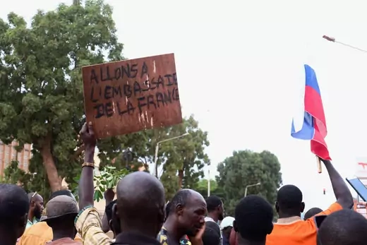 Protesters in Burkina Faso hold up a Russian flag, and a sign that reads "Let's go to the French embassy."