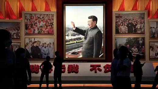 People look at an image of Xi Jinping in a museum.