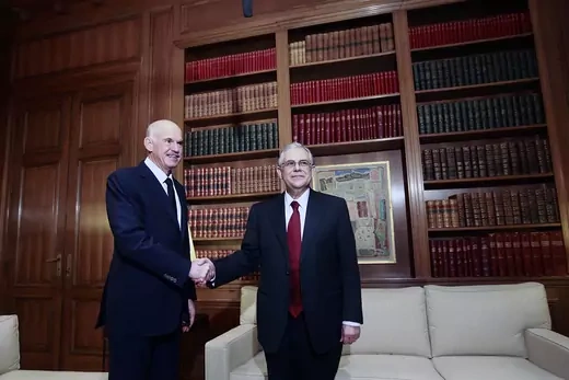 Greek Prime Minister Lucas Papademos shakes hands with outgoing Prime Minister George Papandreou.