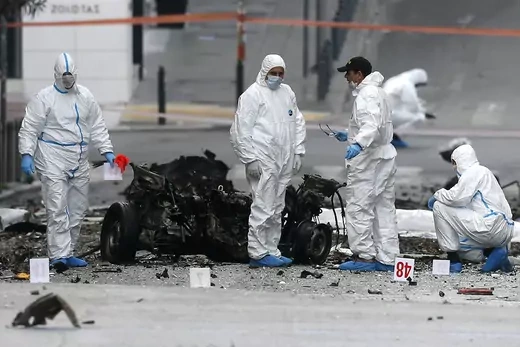 Forensic experts search for evidence on a street where a car bomb went off in Athens. 