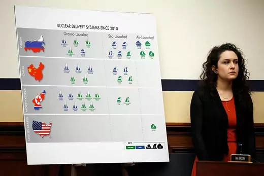 A congressional aide stands next to a poster presenting the administration’s 2018 Nuclear Posture Review.