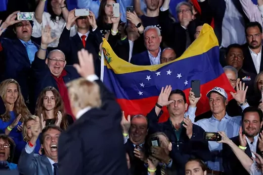 Trump waves to supporters holding a Venezuelan flag.