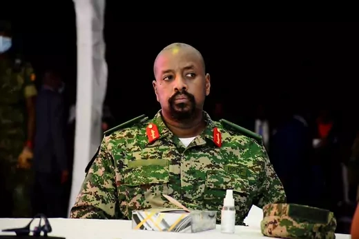 In a green camouflaged military fatigues General Muhoozi Kainerugaba, son of Uganda's President Yoweri Museveni, sits at a table.