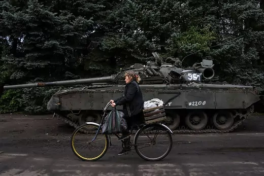 Tank behind woman on bike