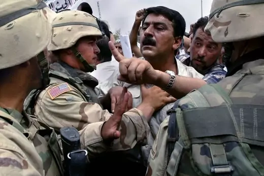 Sacked Iraqi soldiers from the disbanded Iraqi army protest in front of U.S. soldiers next to the headquarters of the U.S.-led administration in Baghdad.