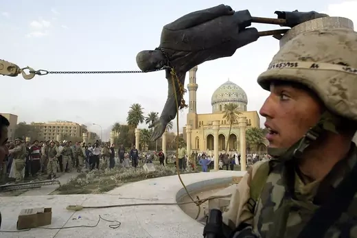 Iraqi civilians and U.S. soldiers pull down a statue of Saddam Hussein in downtown Baghdad