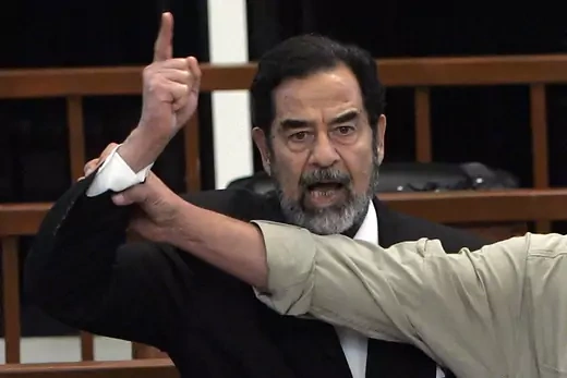 President Saddam Hussein gestures and yells as the court as a bailiff attempts to silence him as the verdict is delivered during his trial.