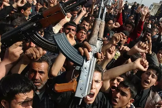  Iraqi Shiite men brandish their weapons as they protest the bombing of a Shiite holy shrine.