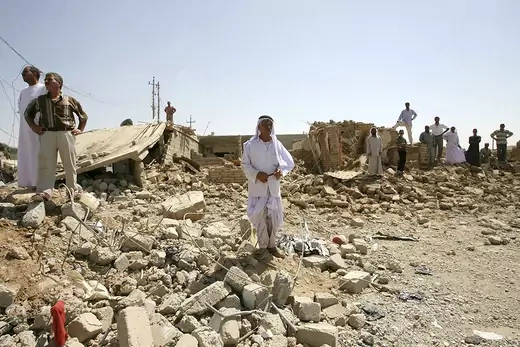 Men stand in rubble at the site of a suicide bomb attack in the village of Kahtaniya, Iraq.