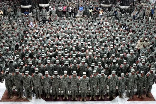A crowd of newly naturalized U.S. soldiers raise their hands during a ceremony at Camp Victory, Baghdad, Iraq.