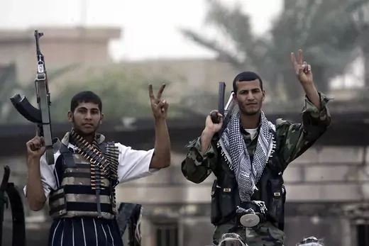 Mehdi Army fighters loyal to cleric Moqtada al-Sadr hold their weapons while flashing the "V" sign.