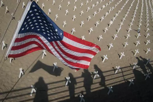 Photo showing the US flag and the shadows of onlookers viewing crosses to commemorate the 4,237 US soldiers killed so far during the war in Iraq. 