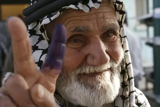 An elderly man with an inked finger flashes a victory sign after he voted at a polling station in Sadr City.