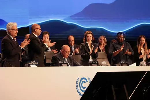 People in suits clap at the end of the COP27 climate summit.