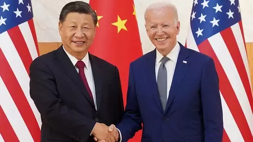 Xi and Biden smile while shaking hands. 