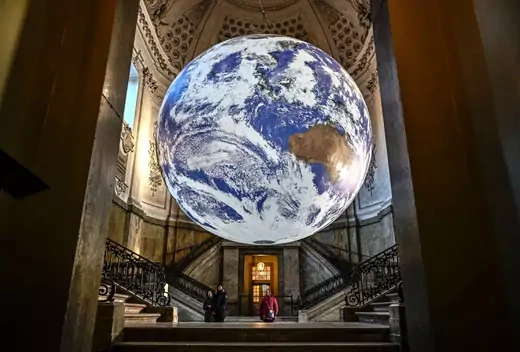 Visitors look at the artwork 'Gaia' created by British visual artist Luke Jerram, which is on display at the Royal Palace's south vault in Stockholm on December 12, 2022