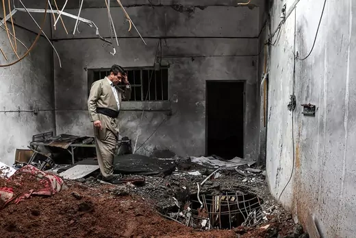 A member of the Kurdistan Democratic Party of Iran inspects damage at the party headquarters following an Iranian air attack