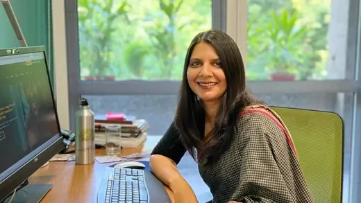 Yamini Aiyar seated at her work desk, smiling.