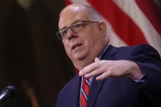 Governor Larry Hogan in the process of raising his hand.