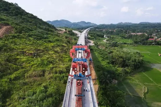 Aerial view of a railway that cuts through lush Indonesian jungle.