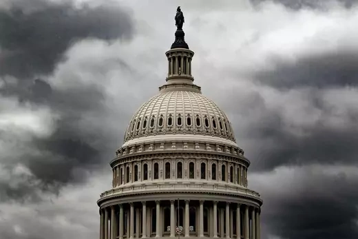 An exterior view of the Capitol dome with storm clouds in the background.