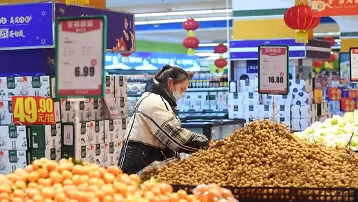 A person browses an aisle of produce in a supermarket in China.
