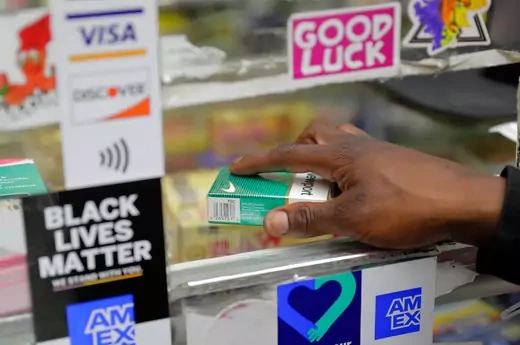 A customer's hand grabs a pack of menthol cigarettes.