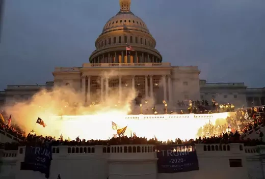 Rioters gather on the steps of the U.S. Capitol on January 6th as a police riot control munition detonates.