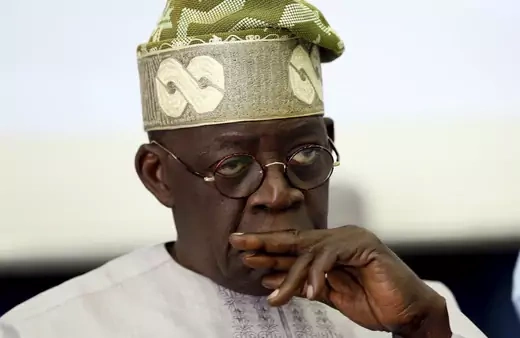 Bola Tinubu, former Lagos state governor, is pictured with a pensive face and his hand to his mouth.