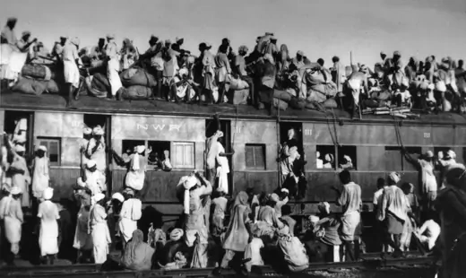 Muslim refugees sit on the roof of an overcrowded coach railway train in trying to flee India.