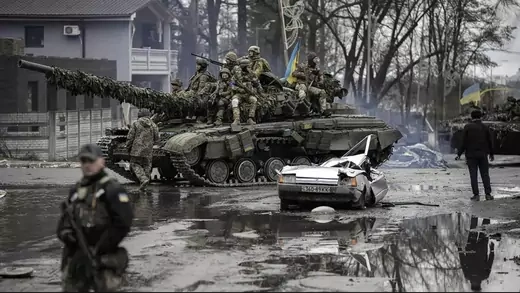 Ukrainian servicemen ride a tank next to a civilian vehicle destroyed during fighting between Russian and Ukrainian forces outside Kyiv, Ukraine, on April 2, 2022.