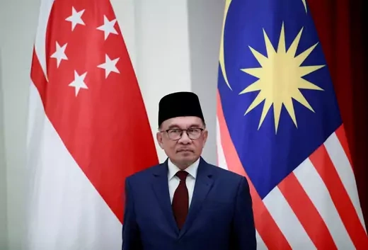 Malaysian Prime Minister stands in front of flags of Singapore and Malaysia