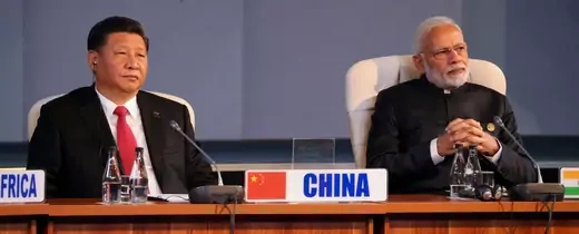 President Xi Jinping of China sits at a table next to President Narendra Modi of India.