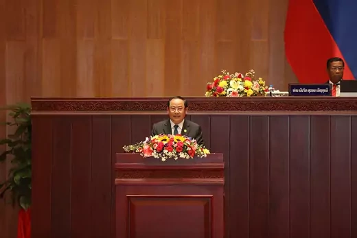 Laos prime minister stands in front of wooden dais. 