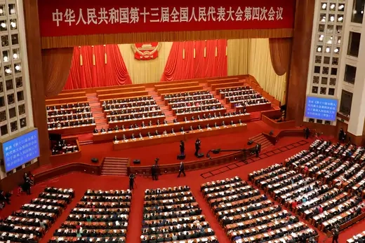 Chinese leaders and delegates attend the closing session of the National People's Congress sit facing the stage, with the camera oriented behind them.