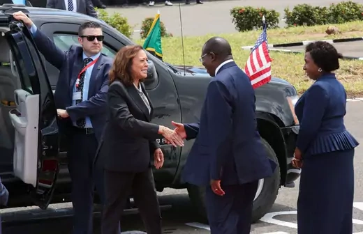 U.S. Vice President Kamala Harris shakes the hand of Tanzanian Vice President Philip Mpango in front of a large black vehicle. 
