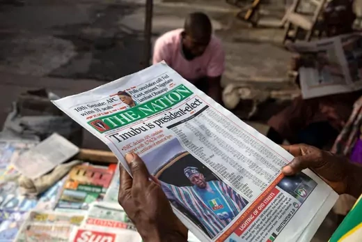 A man reads a newspaper that reads that Bola Ahmed Tinubu has been declared the winner and president-elect of Nigeria.