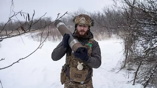 A Ukrainian serviceman carries an artillery shell.