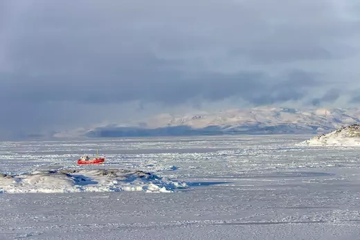 Red icebreaker sails through Arctic ice sheets.