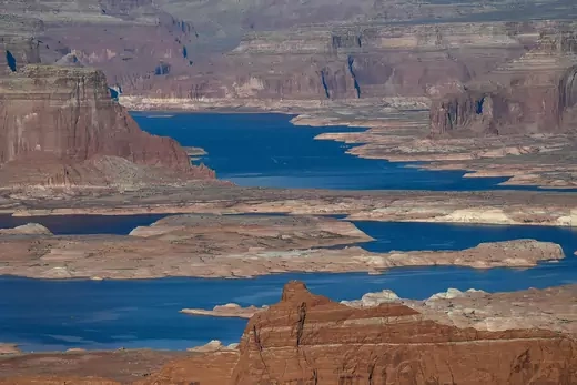 A deep blue river flows between rust-colored mesas.