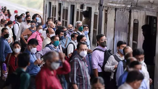 crowd of masked people waiting for train