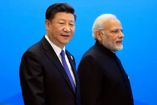 China's President Xi Jinping and India's Prime Minister Narendra Modi stand in front of a bright blue background.