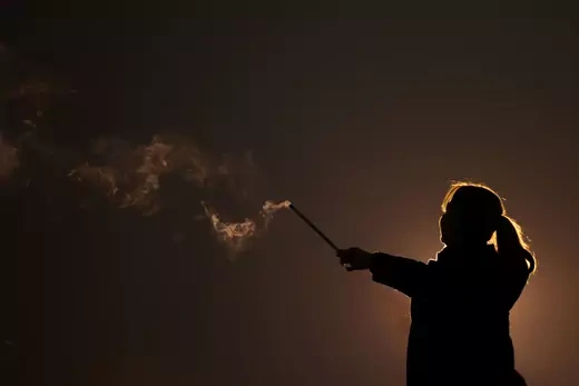 An Iranian woman lights a firework during the Wednesday Fire celebration (Chaharshanbeh Suri in Persian) at a park in Tehran, Iran March 14, 2023.