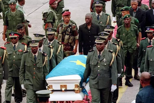 Joseph Kabila Kabange follows the coffin of his father as it is transported by military officers.