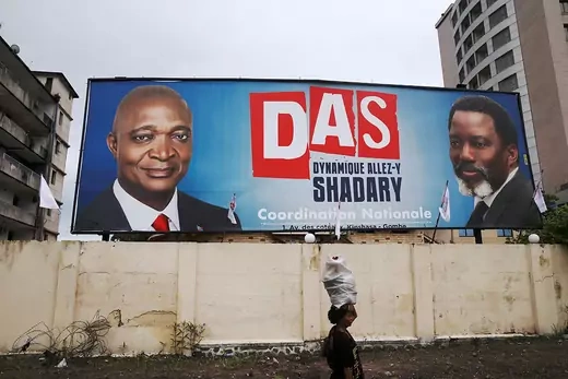 A woman walks past a billboard advertising Kabila’s support for candidate Emmanuel Ramazani Shadary.